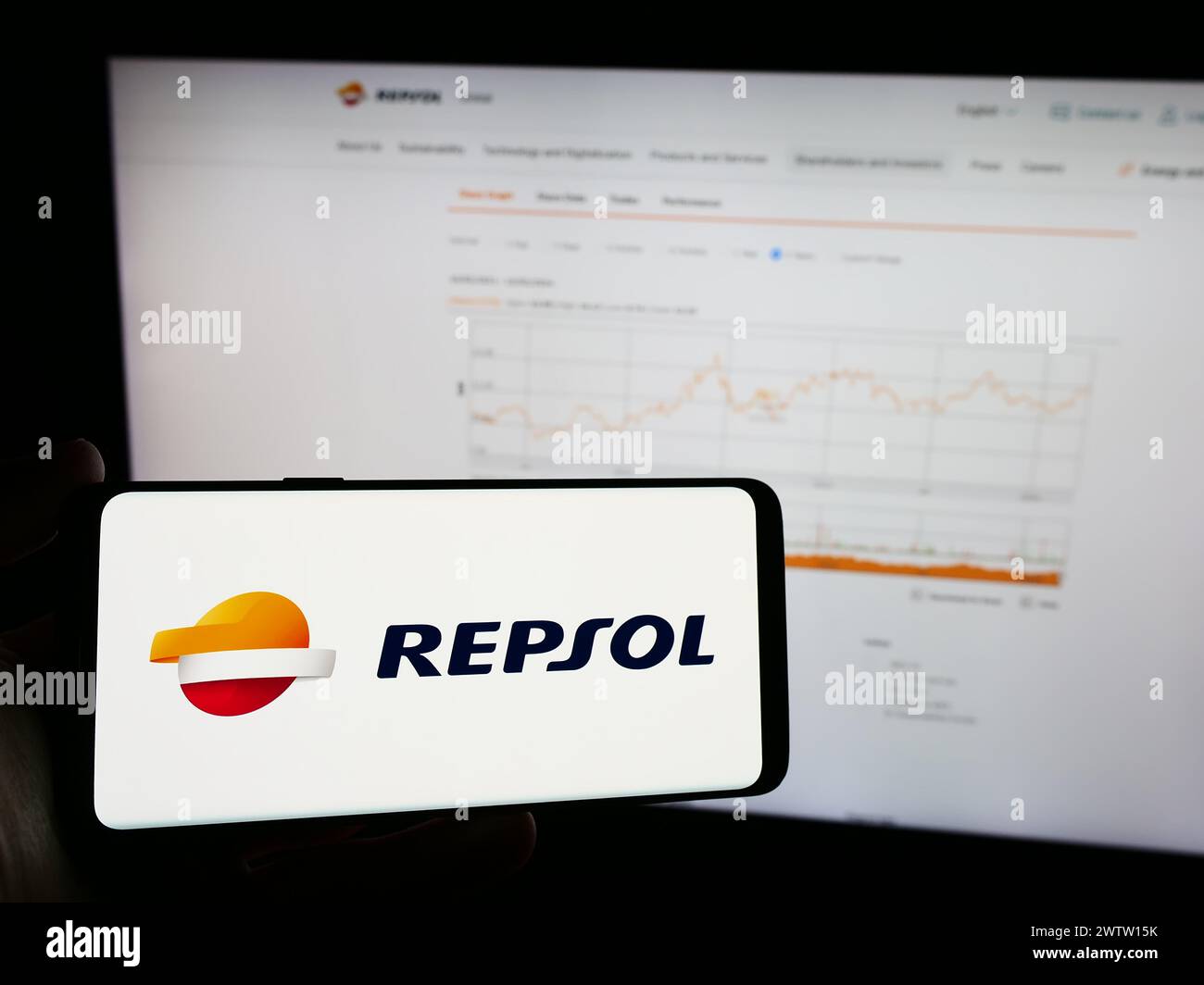 Person, die ein Mobiltelefon mit dem Logo des spanischen Erdölunternehmens Repsol SA vor der Website des Unternehmens hält. Schwerpunkt auf dem Display des Telefons. Stockfoto