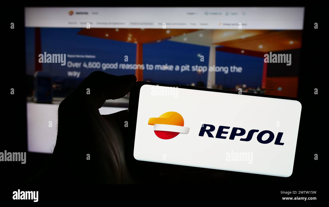 Person mit Smartphone und Logo des spanischen Erdölunternehmens Repsol S.A. vor der Website. Schwerpunkt auf dem Display des Telefons. Stockfoto