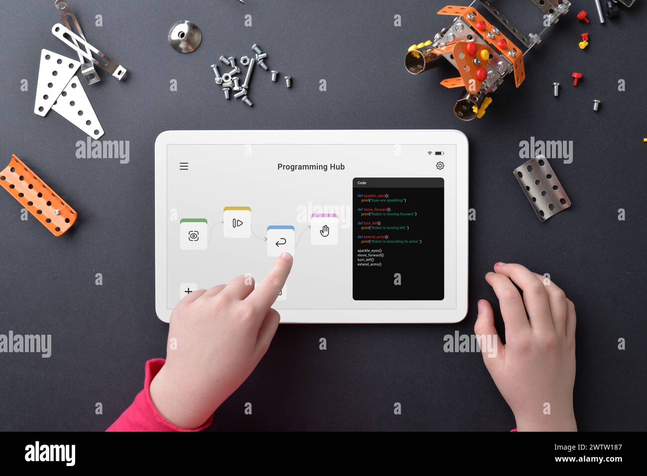 Roboter zum Programmieren von Kindern auf einem Tablet inmitten kleiner Teile auf dem Arbeitstisch. Veranschaulichen von Bildung, Programmierkenntnisse, Kreativität und praxisnahem Lernen Stockfoto