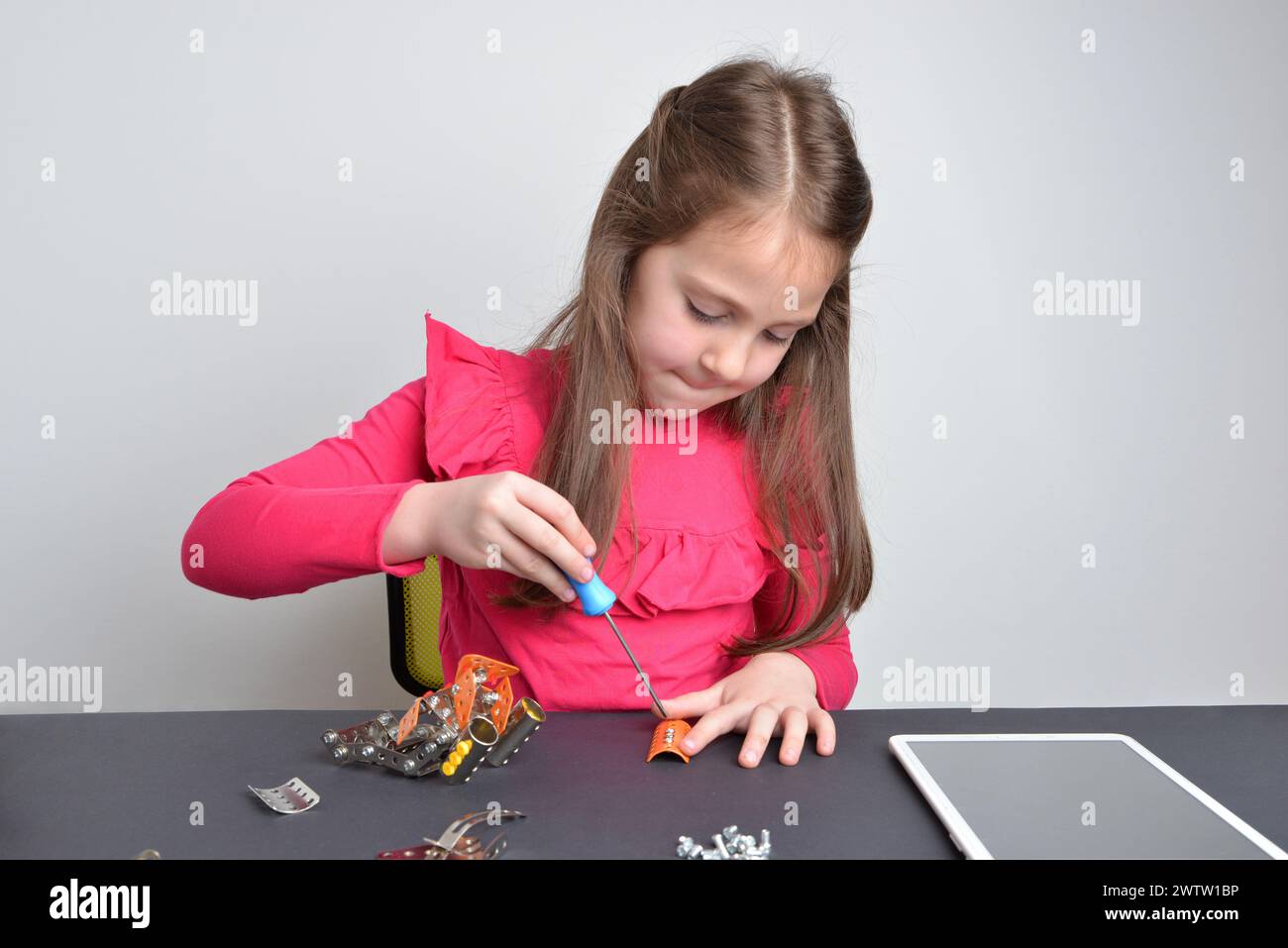 Das kleine Mädchen schraubt Metallteile auf einen Roboter. Konzept des praktischen Lernens, der Bildung, der Kreativität und der technischen Erforschung Stockfoto
