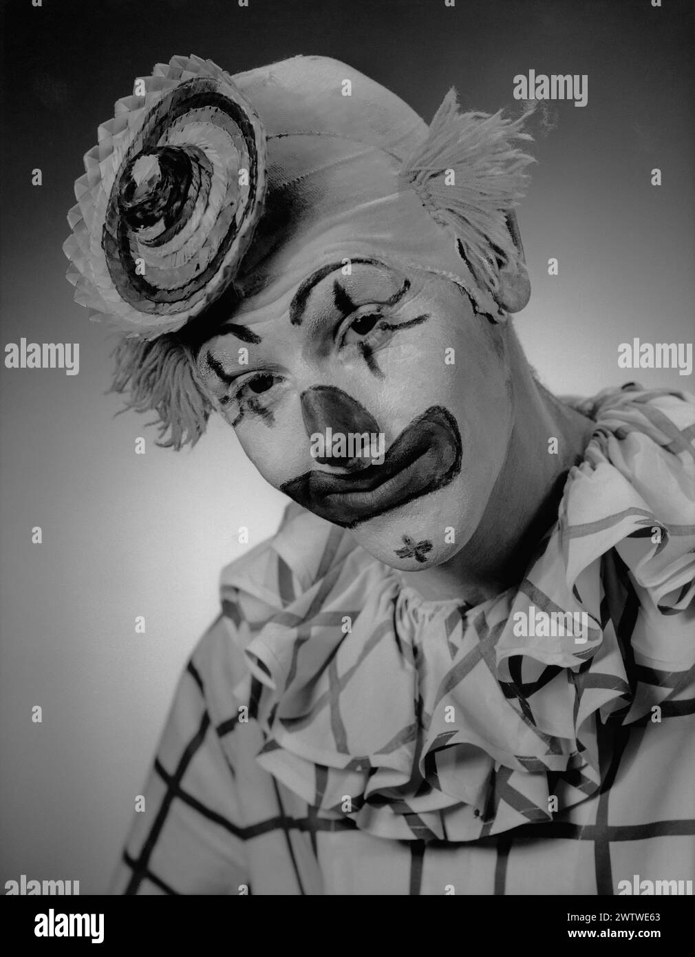 Kopfschuss eines Clown in voller Performance-Make-up mit Mini-Strohhut Stockfoto