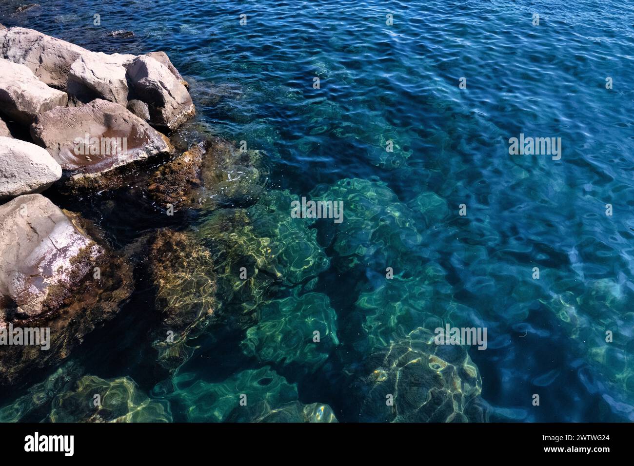 Transparentes aquamarinfarbenes Wasser zeigt untergetauchte Felsen und Kieselsteine und zeigt die Schönheit der Natur unter Wasser Stockfoto