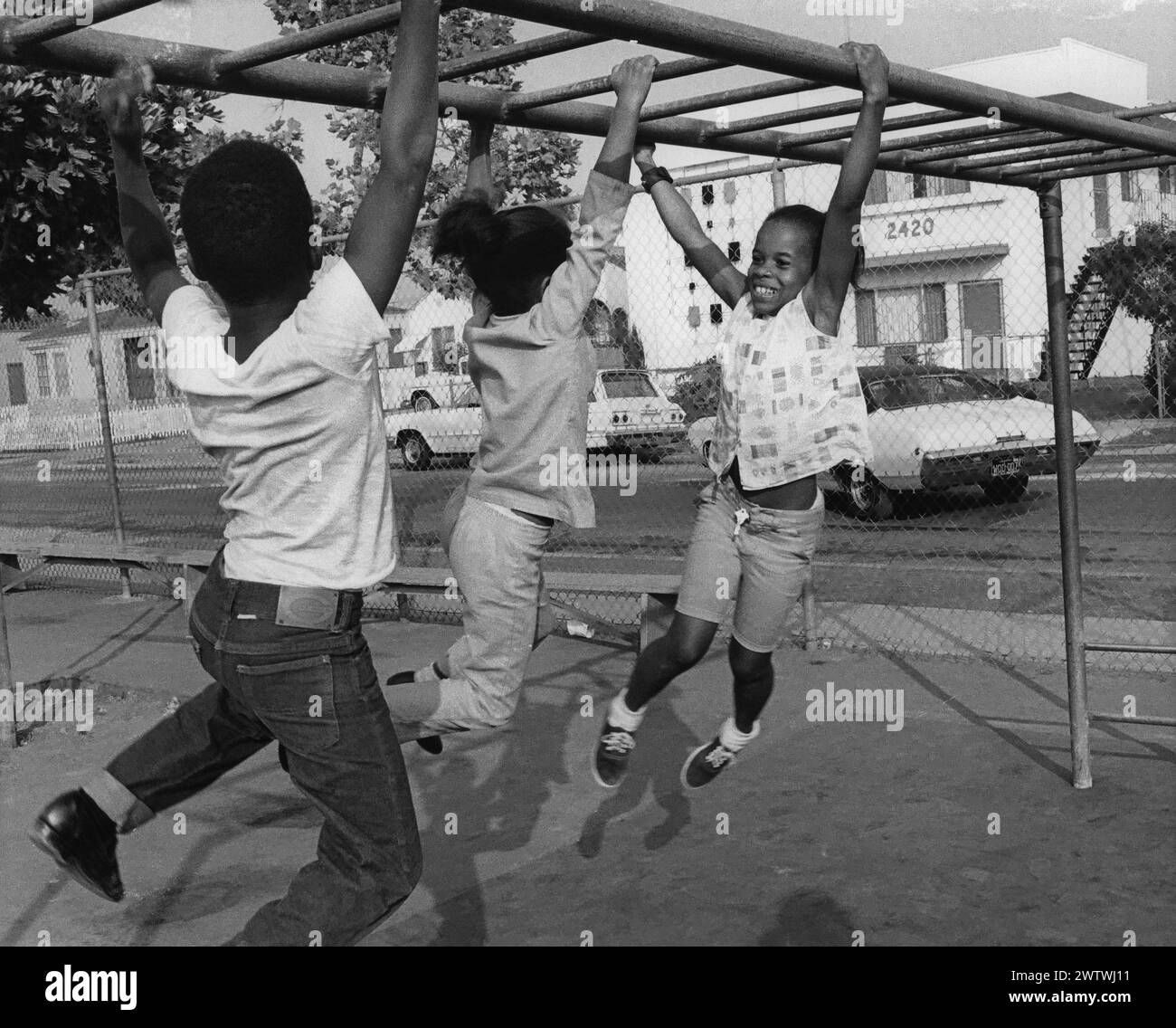 Drei Kinder hängen an den Affenstangen auf dem Spielplatz Stockfoto