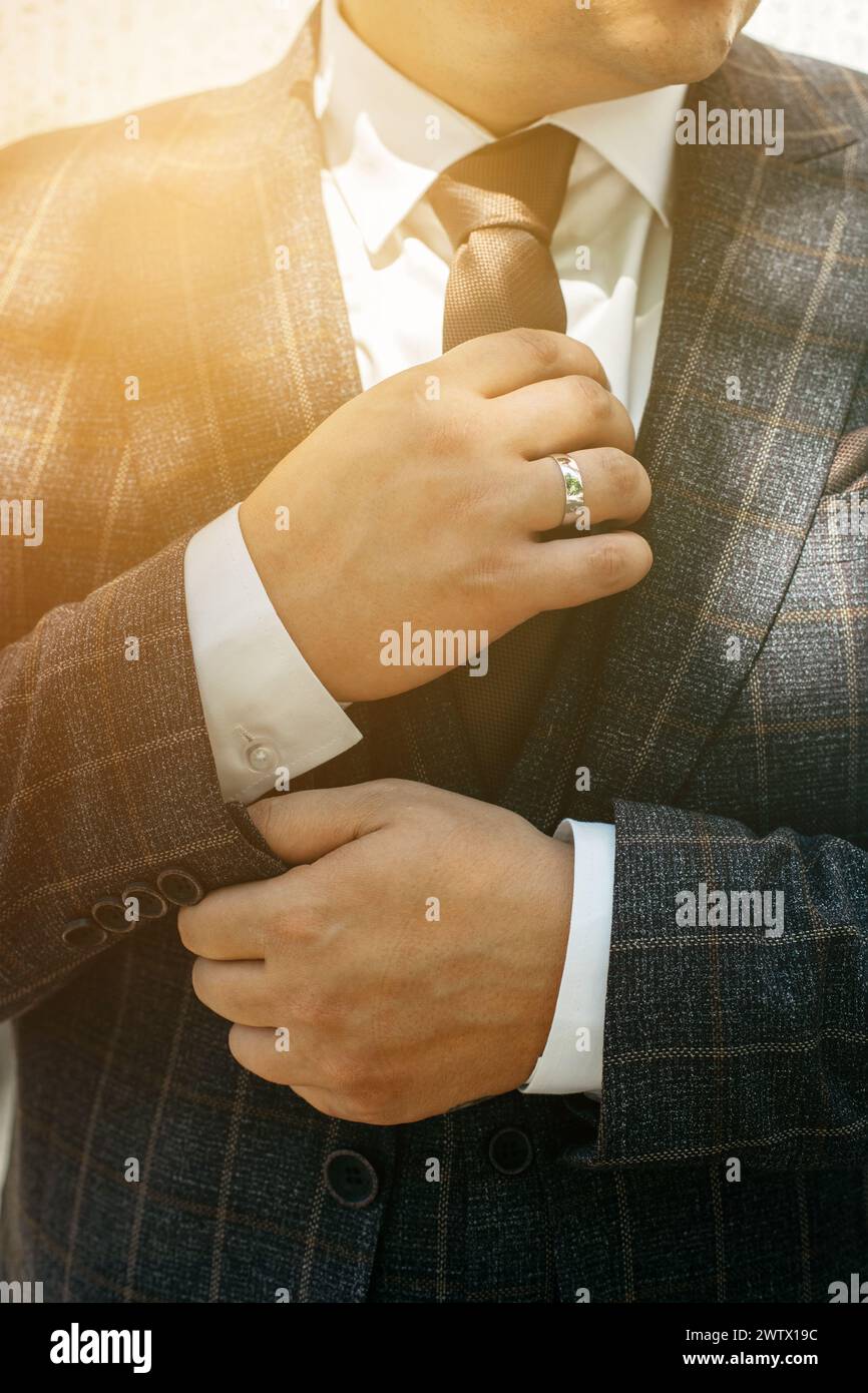 Ein Mann in einem Anzug passt seine Krawatte mit einem konzentrierten Ausdruck an. Stockfoto