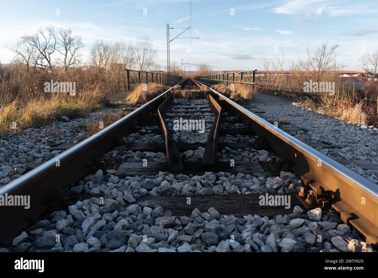 Schienen mit Holzbinder und Freileitung an sonnigen Abenden, Eisenbahntransport Stockfoto