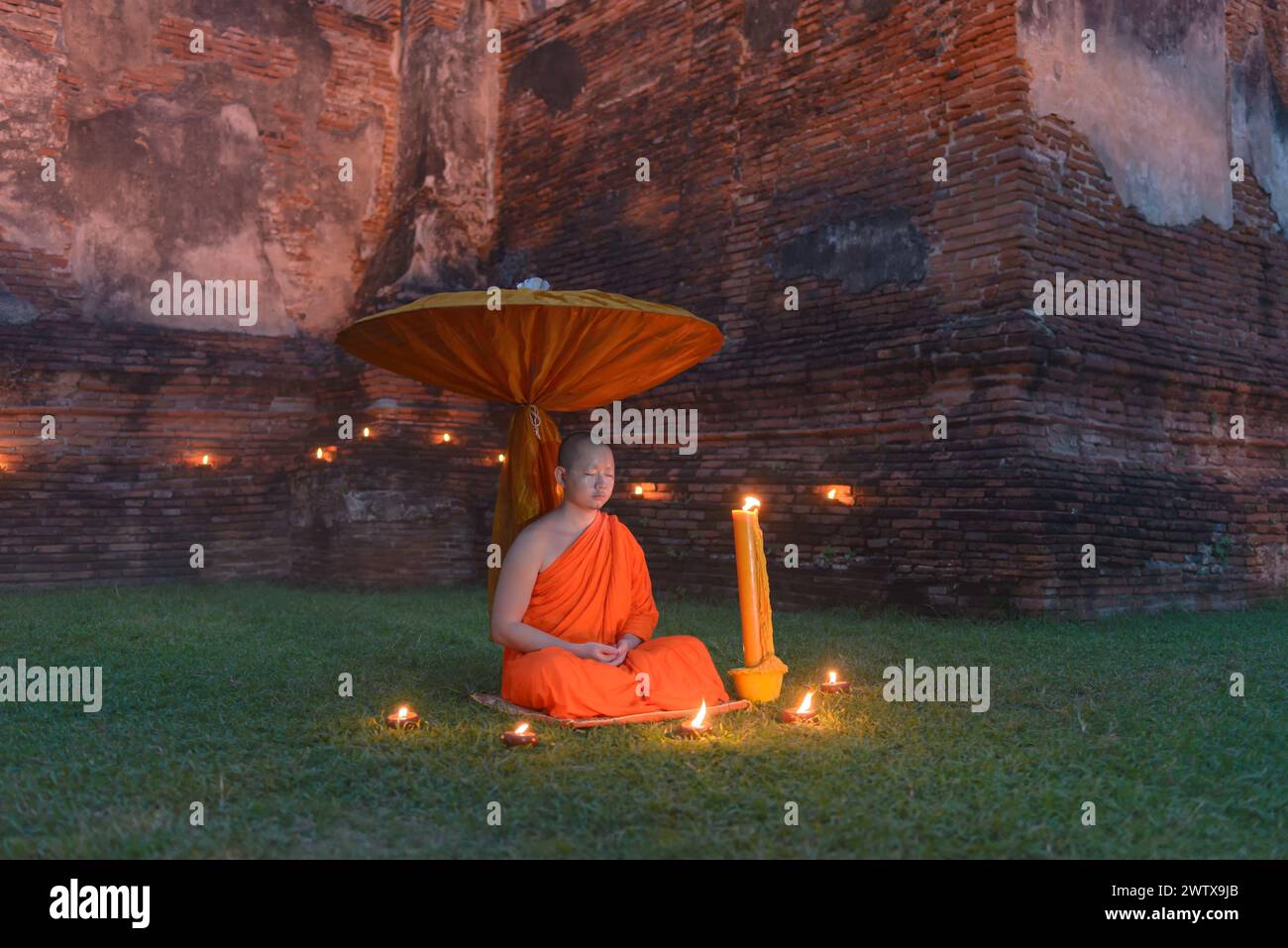 Buddhistischer Mönch sitzt draußen und meditiert bei Sonnenuntergang, Ayutthaya, Thailand Stockfoto