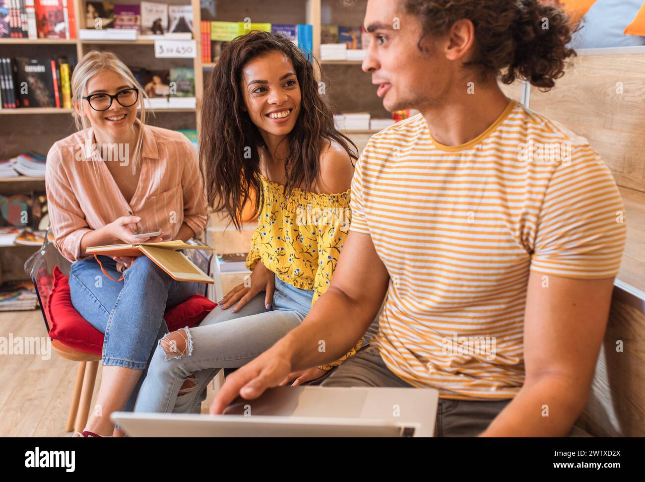 Porträt junger männlicher Studentinnen in der Bibliothek mit Laptop für Online-Recherchen. Stockfoto