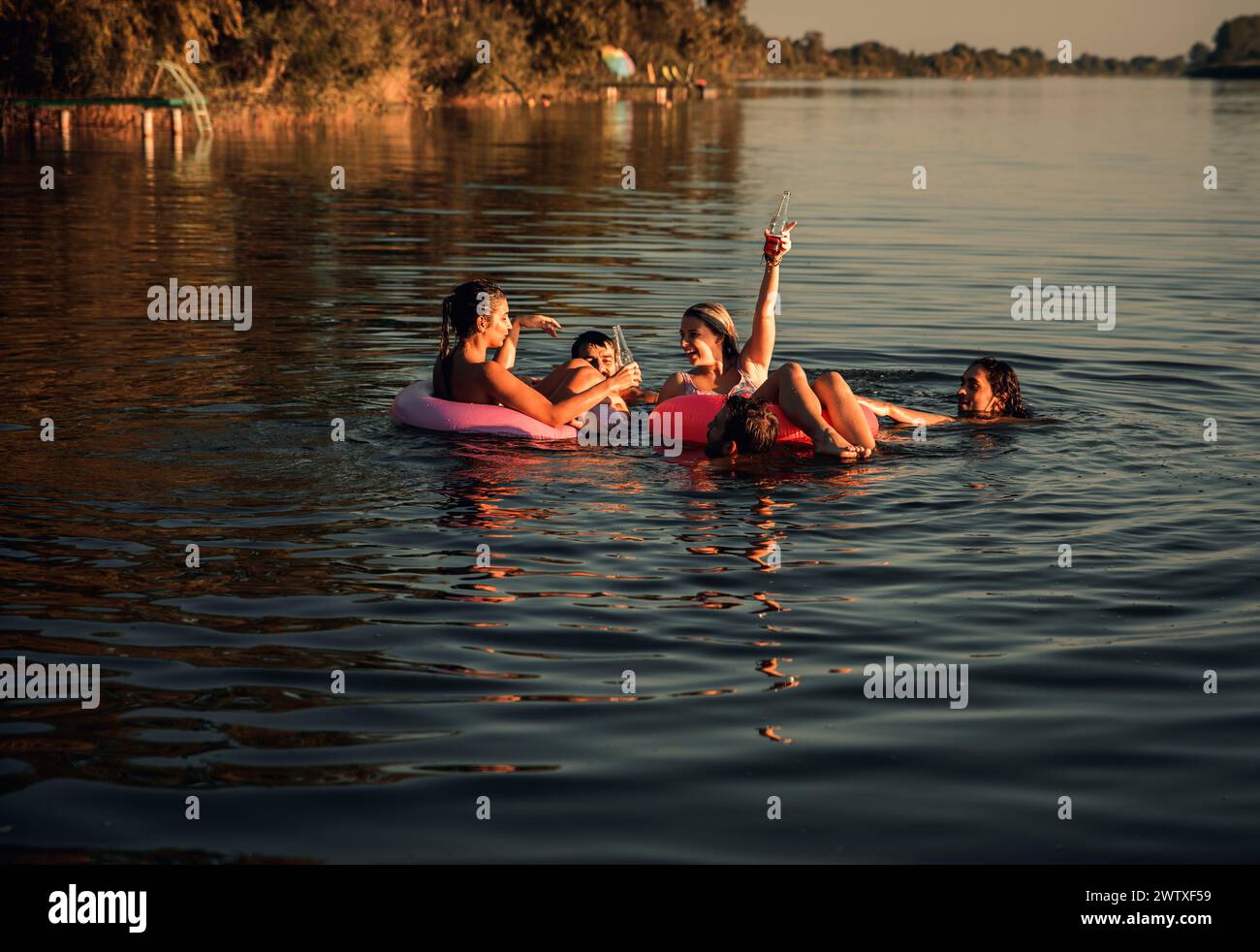 Gruppe von jungen Freunden, die Spaß haben und einen Sommertag beim Schwimmen am See genießen. Stockfoto