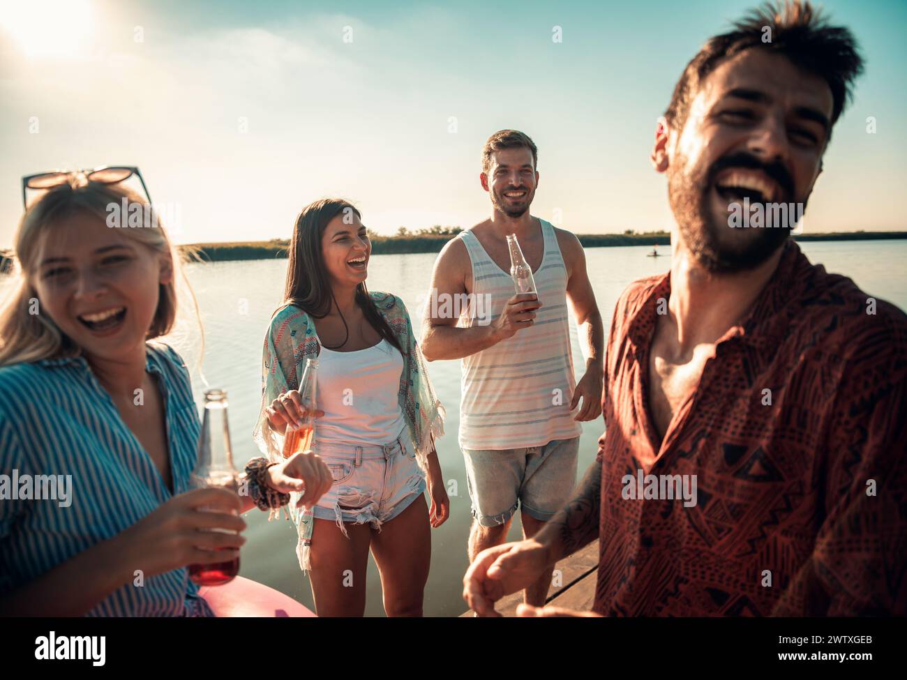 Gruppe von Freunden, die an einem Pier stehen und Spaß haben und einen Sommertag am See genießen. Stockfoto