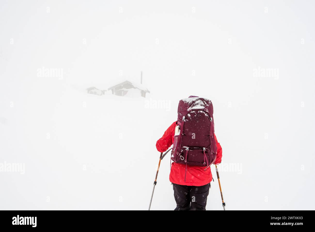 Ein Skitourenfahrer, der in Richtung einer Berghütte bei schlechter Sicht in Jotunheim, Norwegen, fährt Stockfoto
