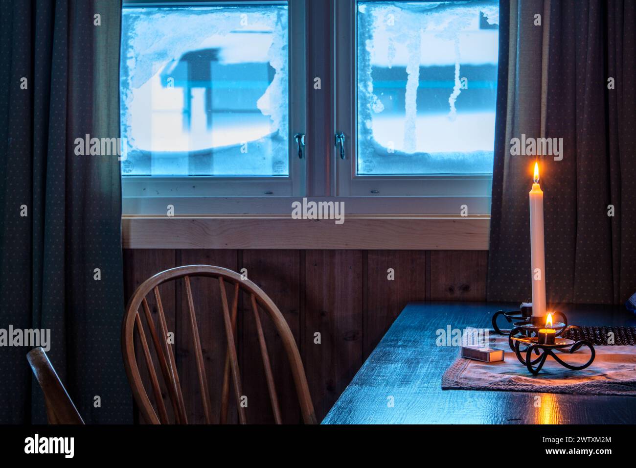 Eine Kerze im Fenster einer norwegischen Hütte im Winter Stockfoto