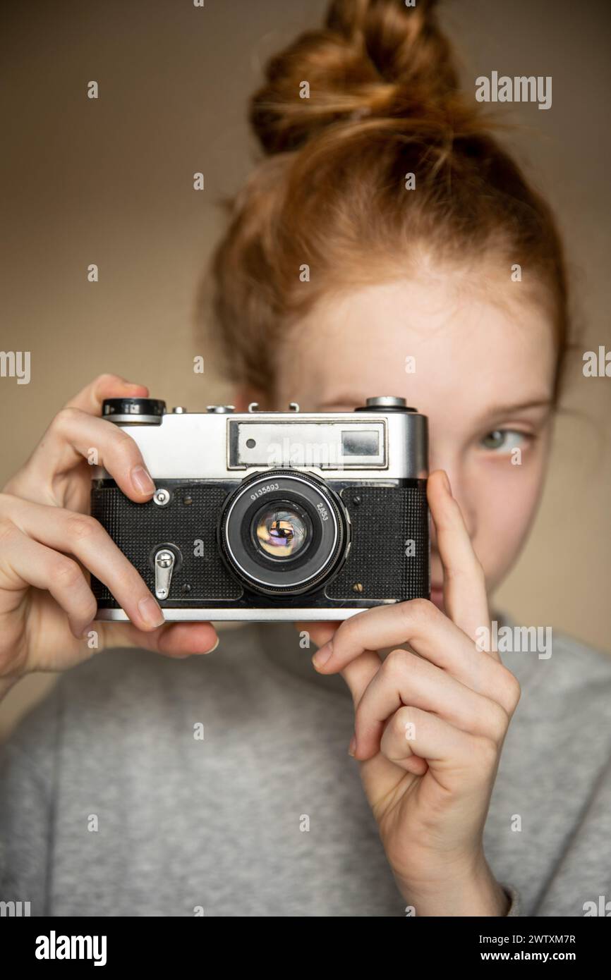 Film-Retro-Kamera in den schönen Händen eines jungen rothaarigen Mädchens Stockfoto