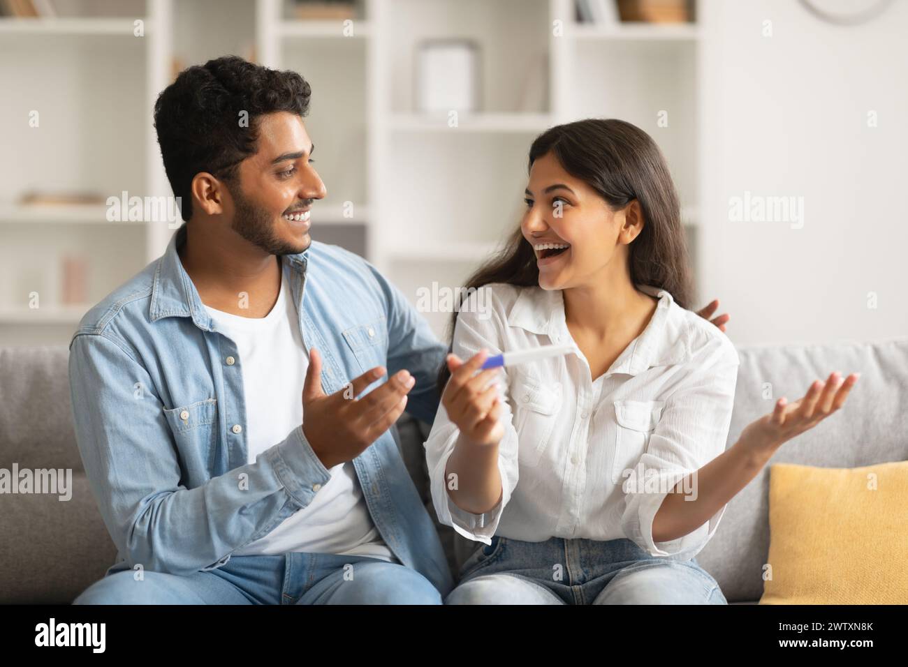 Fröhliche indische Ehegatten mit Schwangerschaftstest, aufgeregte Reaktion Stockfoto