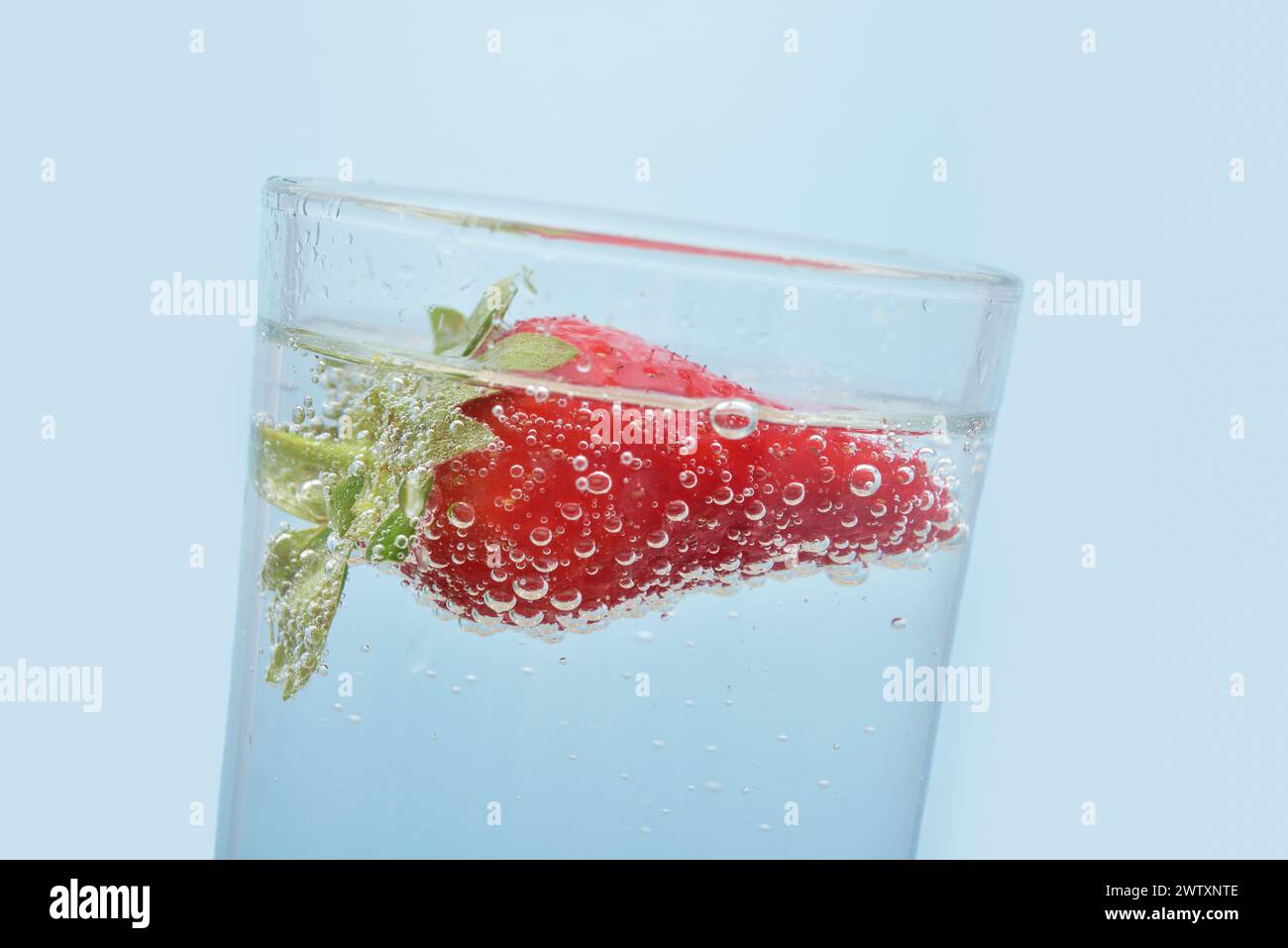 Foto einer Erdbeere in Mineralwasser in einem Glas. Details einer Beere und Wasserblasen aus nächster Nähe. Stockfoto