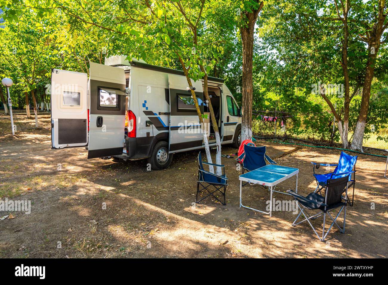 Wohnmobil mit Campingausrüstung auf dem Campingplatz geparkt. Das Wohnmobil mit Etagenbetten steht auf dem Campingplatz unter den Bäumen in Meteora, Greec, parkt Stockfoto