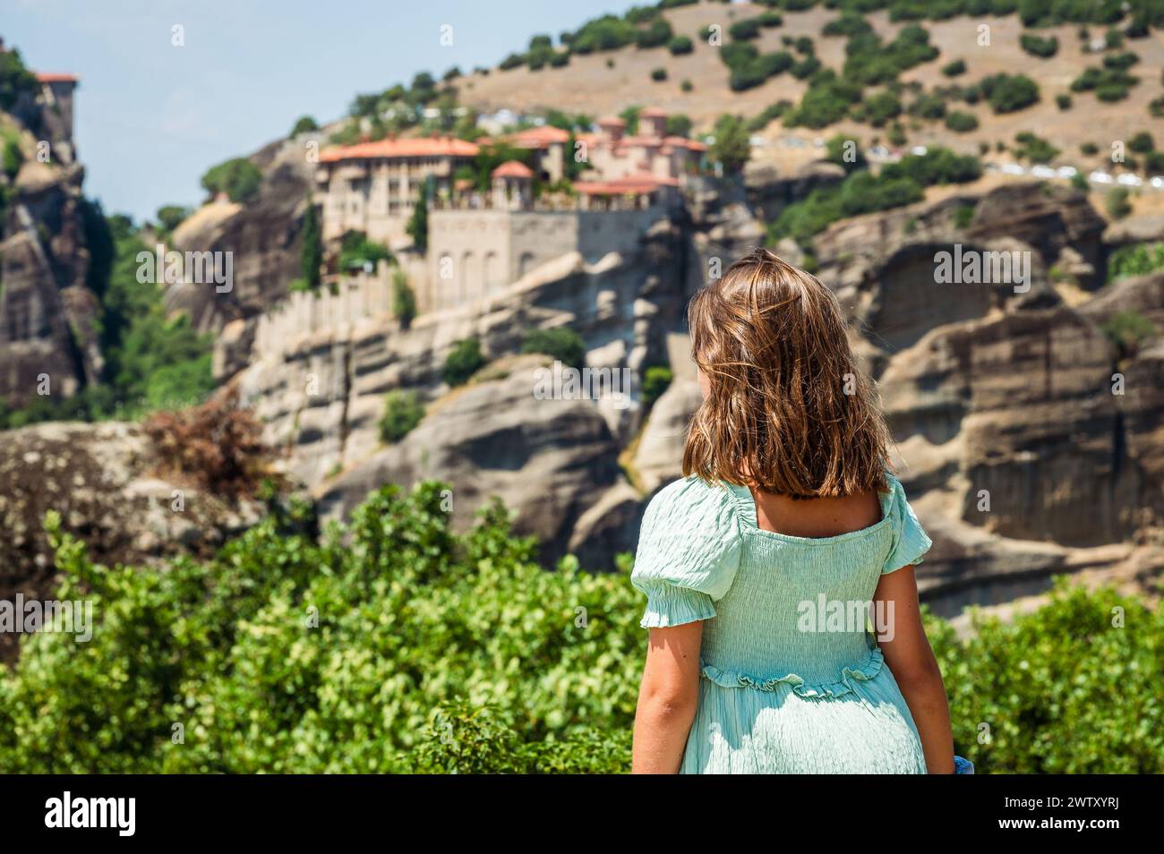 Porträt von Kindern, die das berühmte Meteora-Kloster in Griechenland besuchen. Mädchen schaut sich das berühmte Kloster Meteora an einem sonnigen Sommertag an. Stockfoto