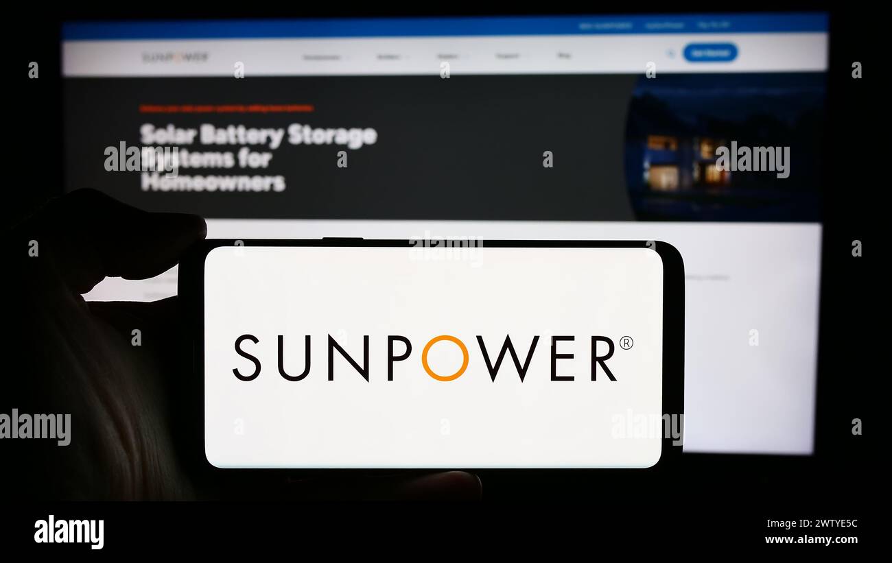 Person mit Smartphone und Logo des US-amerikanischen Photovoltaikunternehmens SunPower Corporation vor der Website. Schwerpunkt auf dem Display des Telefons. Stockfoto