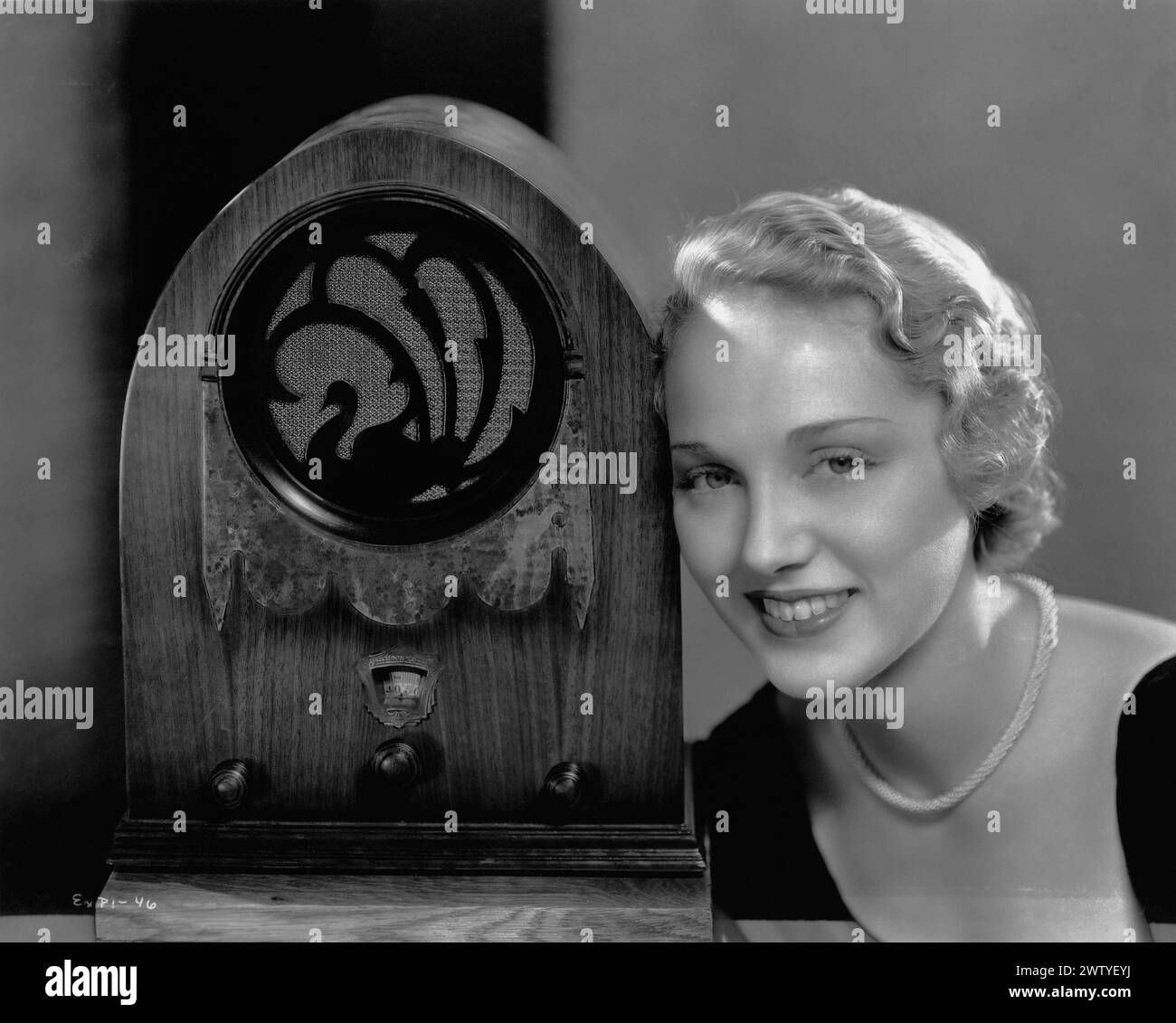 Schauspielerin Leila Hyams blickt nach vorne in die Kamera, während sie ihren Kopf auf einem altmodischen Radio ruht Stockfoto