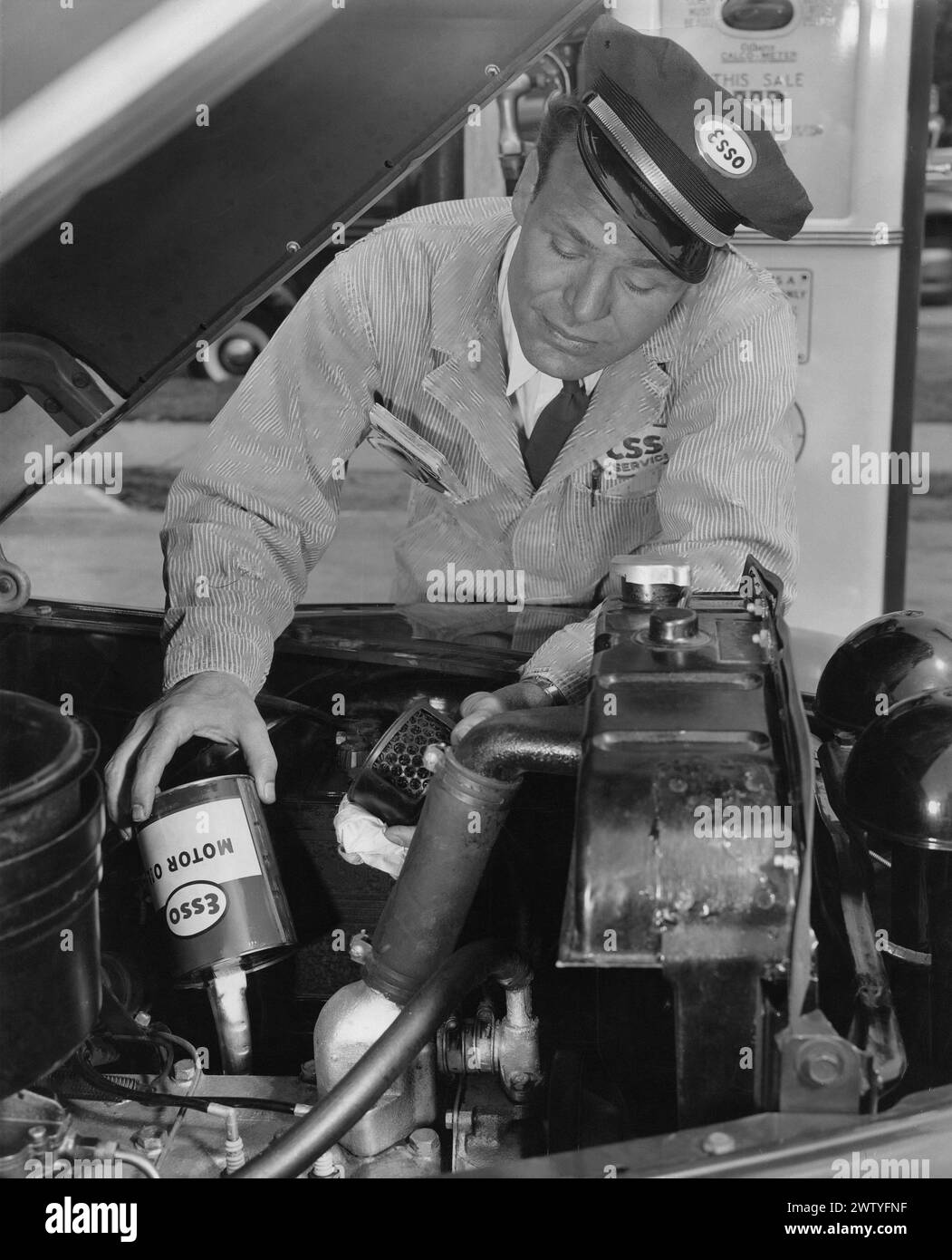 Ein Mitarbeiter der Servicestation hat ein Fahrzeug mit ESSO-Öl befüllt Stockfoto