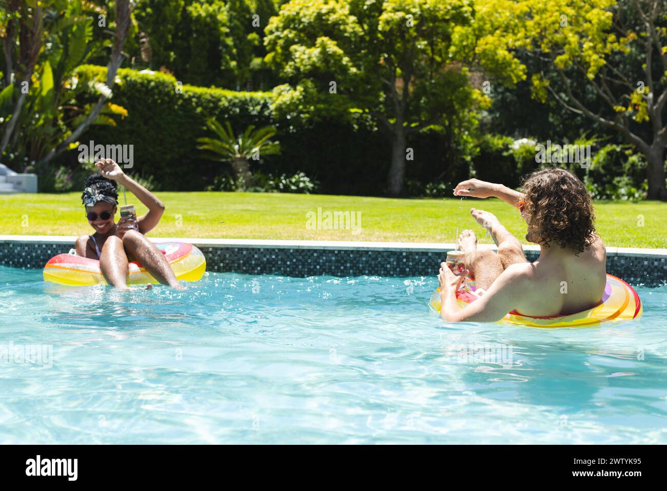 Ein vielseitiges Paar genießt einen sonnigen Tag im Pool Stockfoto