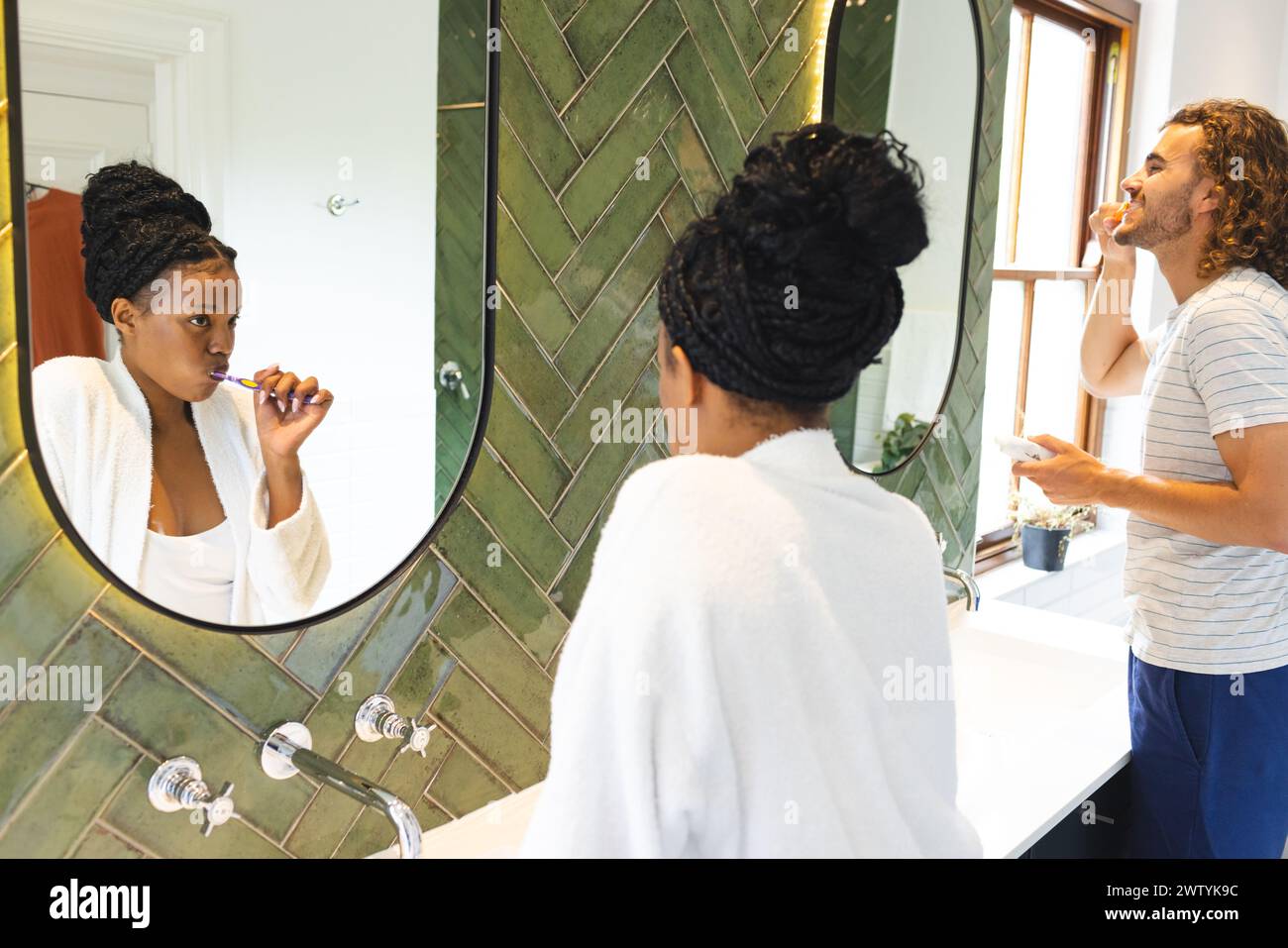 Ein vielseitiges Paar pflegt und putzt die Zähne in einem gut beleuchteten Badezimmer Stockfoto