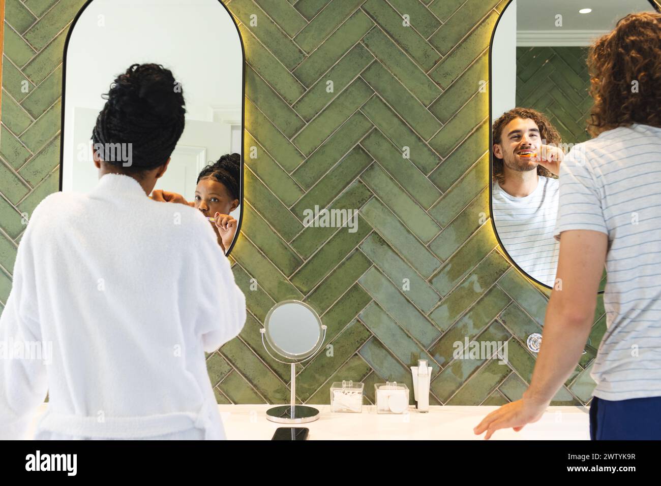 Ein vielseitiges Paar pflegt und putzt die Zähne in einem hellen Badezimmer Stockfoto