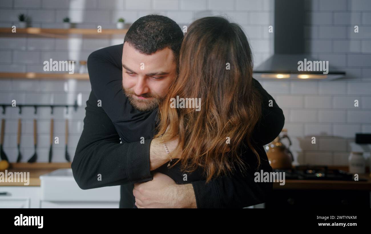 Rückansicht einer Frau, die ihren Liebhaber umarmt. Romantischer Mann, der seine Freundin in der Küche umarmt. Mittlere Nahaufnahme Kuscheln geliebtes junges Paar Stockfoto