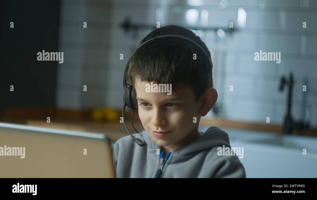 Nahaufnahme eines Schülers, der ein schnurloses Headset trägt, während eines Videogesprächs mit einem Laptop online kommuniziert und dem Lehrer zuhause zuhört. Online-Pfleger Stockfoto