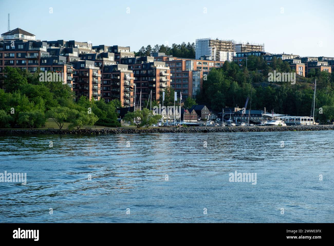 Nacka Strand Yachthafen im Stockholmer County, Archipel Schweden. Gebäude am Meer, vertäute Yacht im Steg, ruhiges Meerwasser, Sommertag. Stockfoto