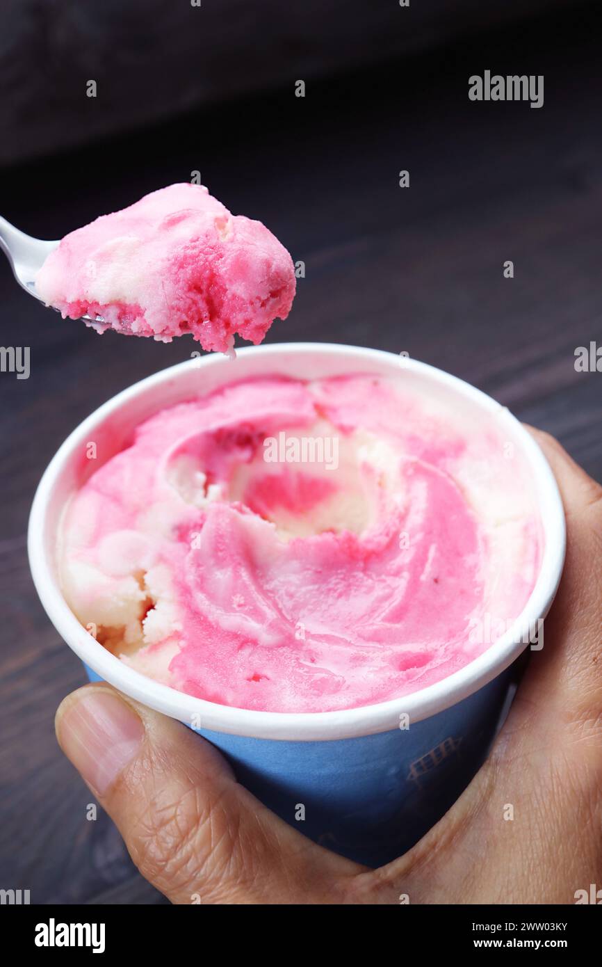 Löffel mit köstlichem Erdbeerjoghurt-Eis aus einer Tasse Stockfoto