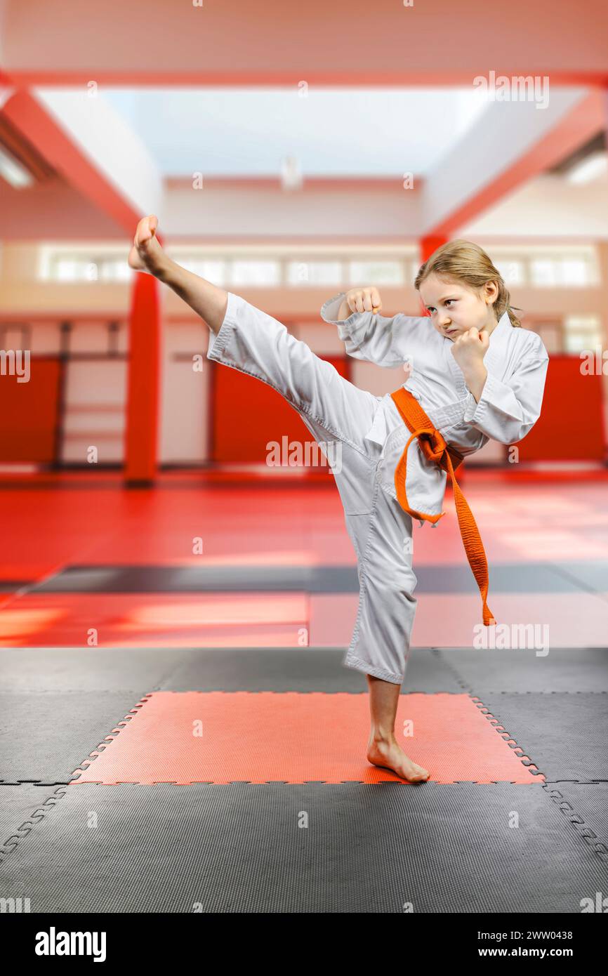 Mädchen in Karate-Uniform, das einen hohen Kick durchführt Stockfoto
