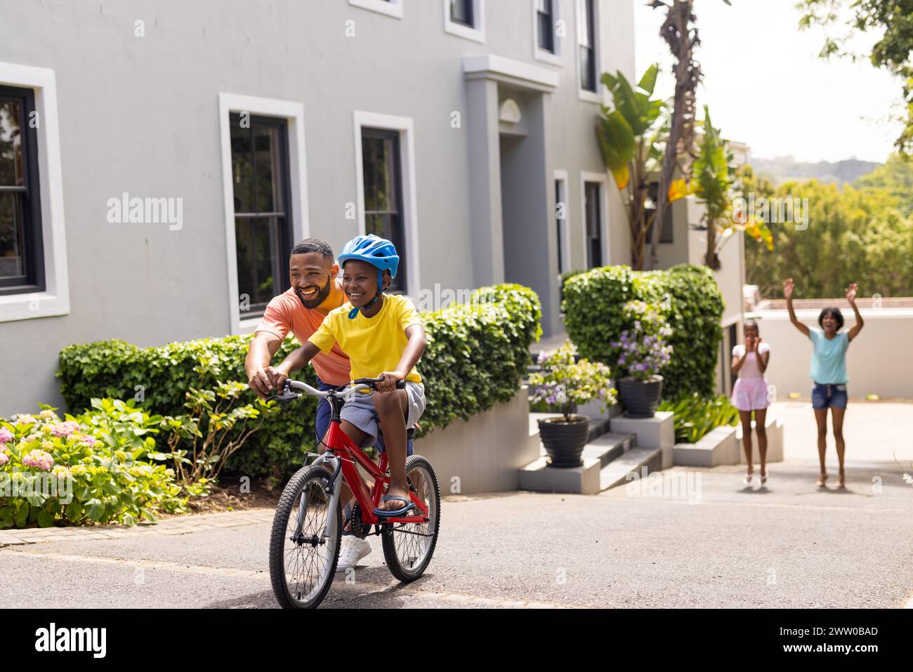 Ein afroamerikanischer Vater bringt seinem Sohn bei, draußen Fahrrad zu fahren Stockfoto