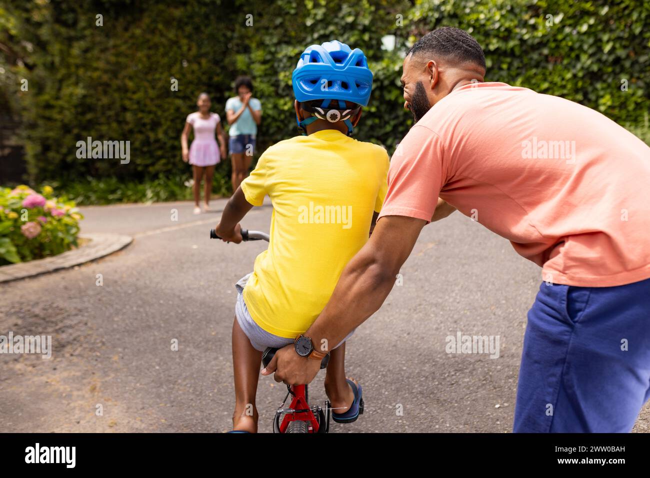 Ein afroamerikanischer Vater bringt dem Sohn bei, draußen Fahrrad zu fahren Stockfoto