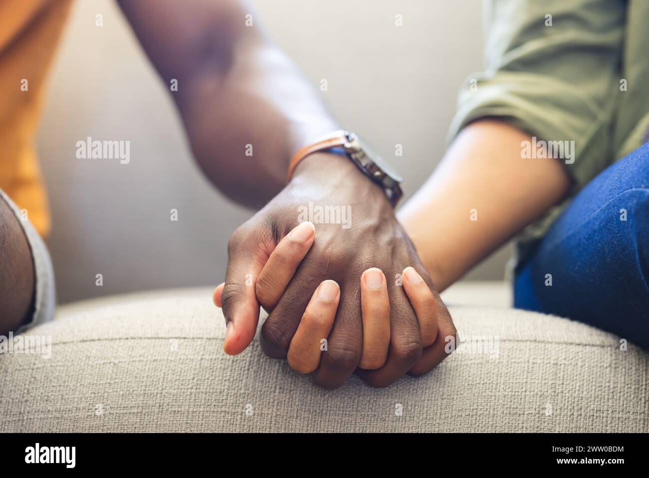 Ein vielseitiges Paar hält Hände auf der Couch und zeigt Einheit und Zuneigung Stockfoto