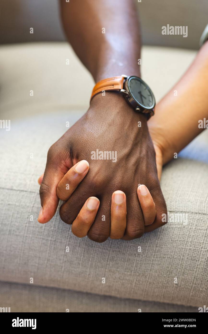 Ein vielseitiges Paar hält Hände auf einer Couch und zeigt Einheit und Zuneigung Stockfoto