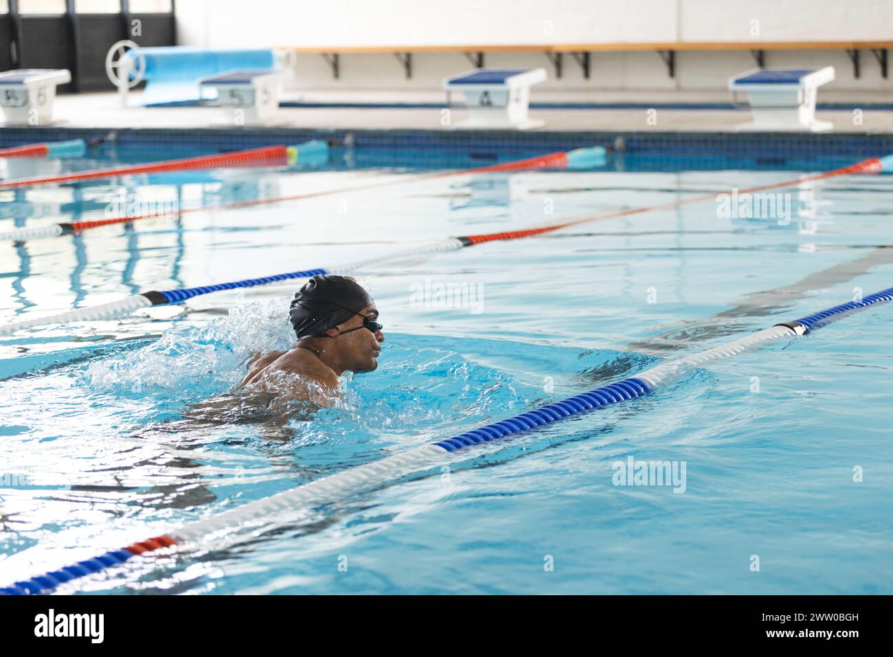Ein junger afroamerikanischer Sportler schwimmt in einem Innenpool mit Kopierbereich Stockfoto