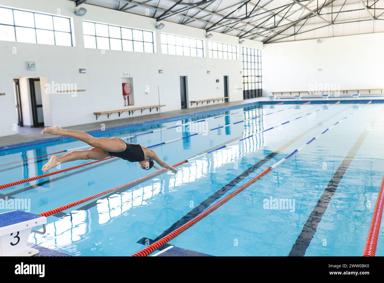 Eine kaukasische Sportlerin taucht in einen klaren blauen Pool mit Kopierraum Stockfoto