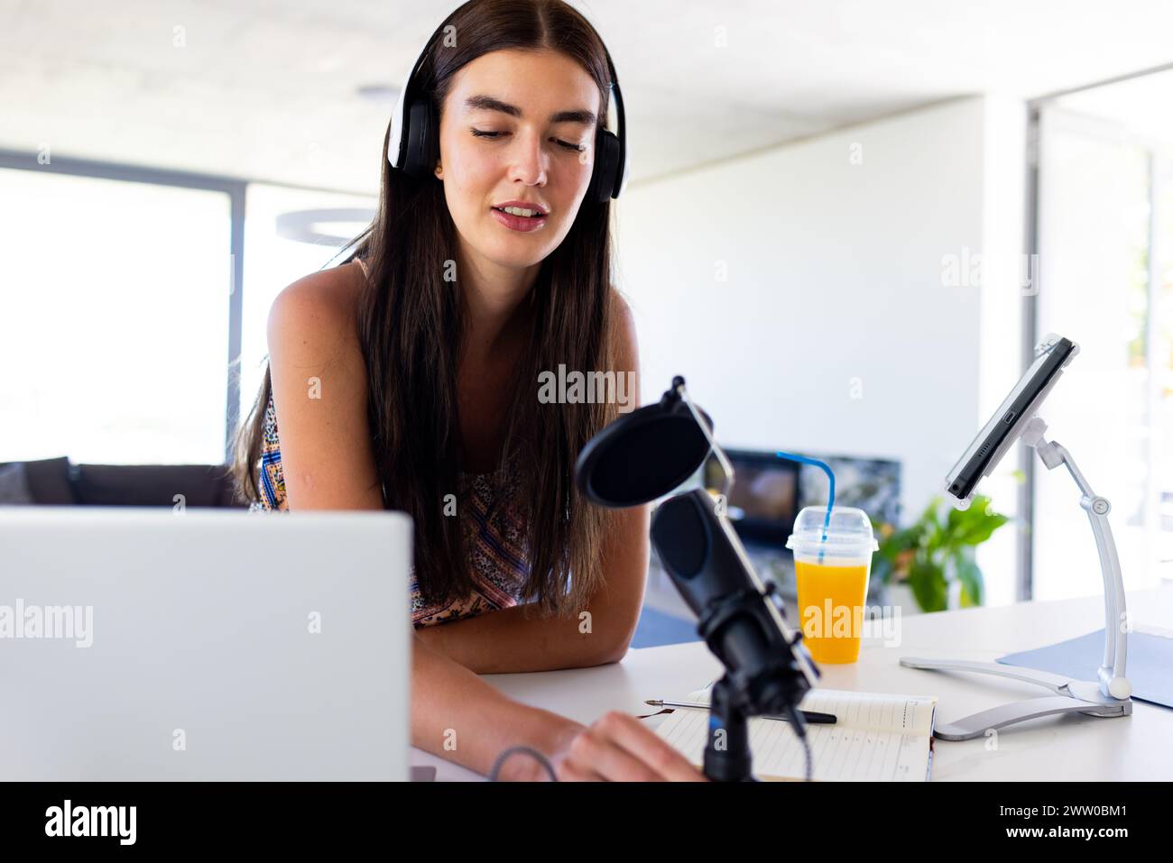 Eine junge weiße Brünette nimmt zu Hause einen Podcast auf Stockfoto