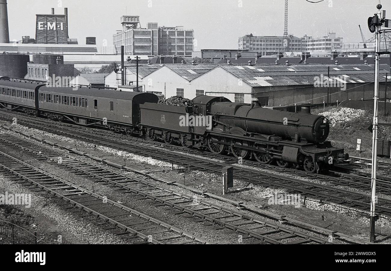 1950er Jahre, historische Dampflokomotive der Briitsh Railways, 6864, Dymock Grange, auf der Bahnstrecke, mit Kohlewagen und Wagen, England, Großbritannien. Die 4-6-0-Lokomotive der Great Western Railways (GWR) wurde 1939 gebaut und dem Schuppen in Old Oak Common zugeordnet. 1947 wurde sie Reading und 1955 nach Oxford versetzt. 1965 wurde sie aus dem Dienst genommen und im folgenden Jahr abgesetzt. Stockfoto