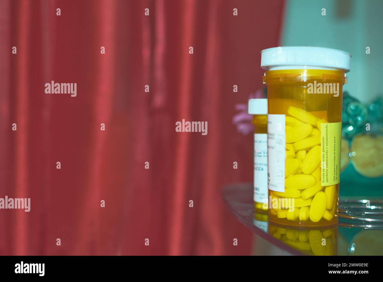 Gelbe Medikamentenflasche, weißes Etikett, roter Hintergrund. Stockfoto