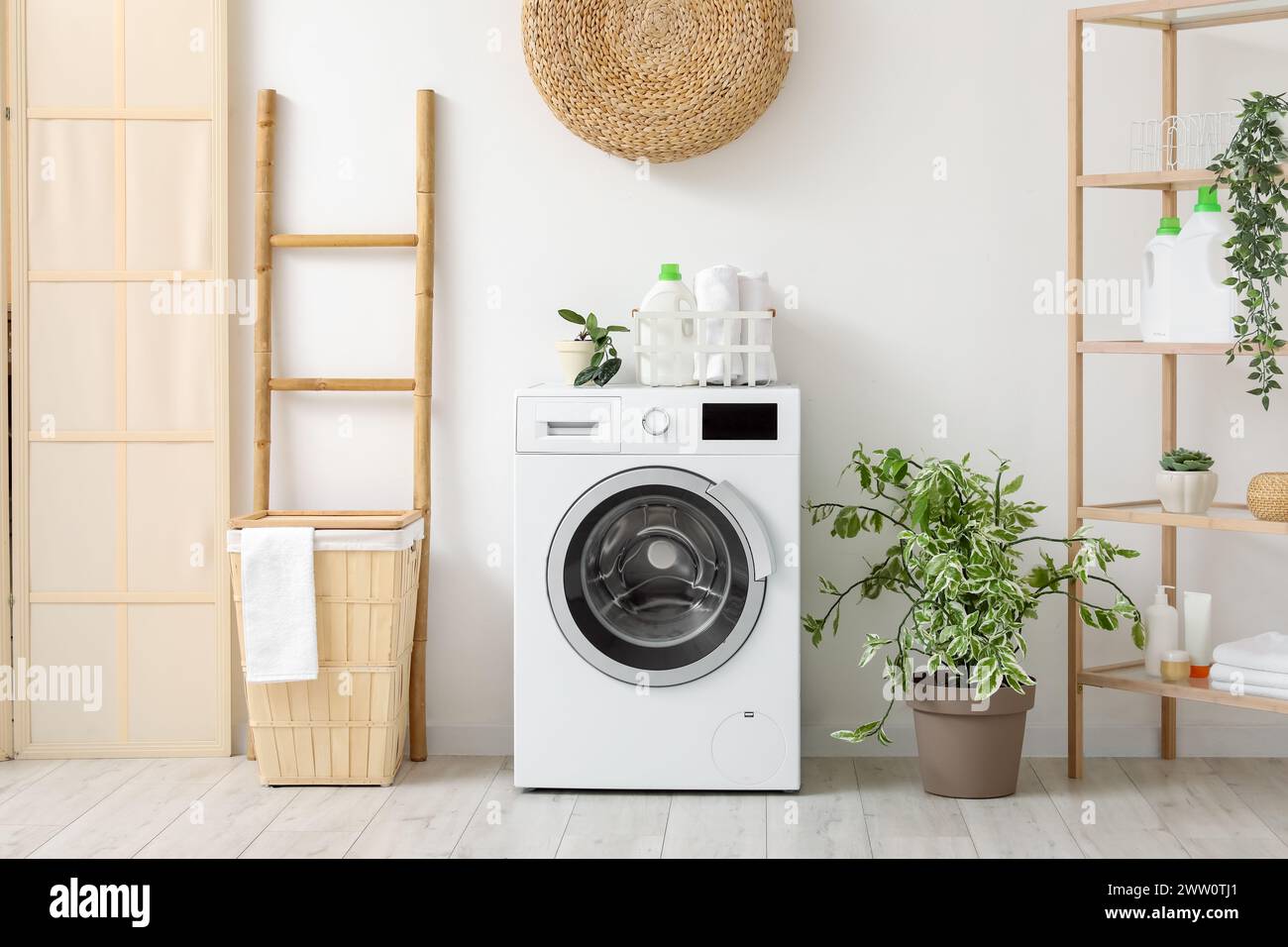 Moderne Waschmaschine mit Korb, Regalfach und Leiter in der Nähe der weißen Wand. Innenraum des Waschraums zu Hause Stockfoto