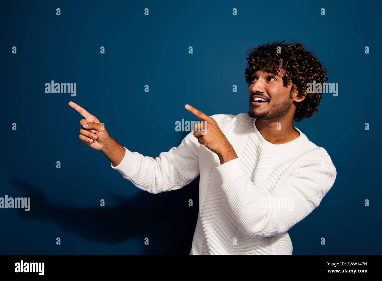 Foto eines jungen Mannes in weißem Pullover, der Finger-Plakatwerbung zeigt neues mcdonalds-Menü mexiko isoliert über dunkelblauem Hintergrund Stockfoto