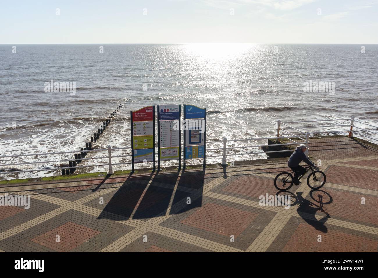 Ein Mann radelt vorbei an den Strandschildern auf dem Beaconsfield Prom in Bridlington, Yorkshire, Großbritannien Stockfoto