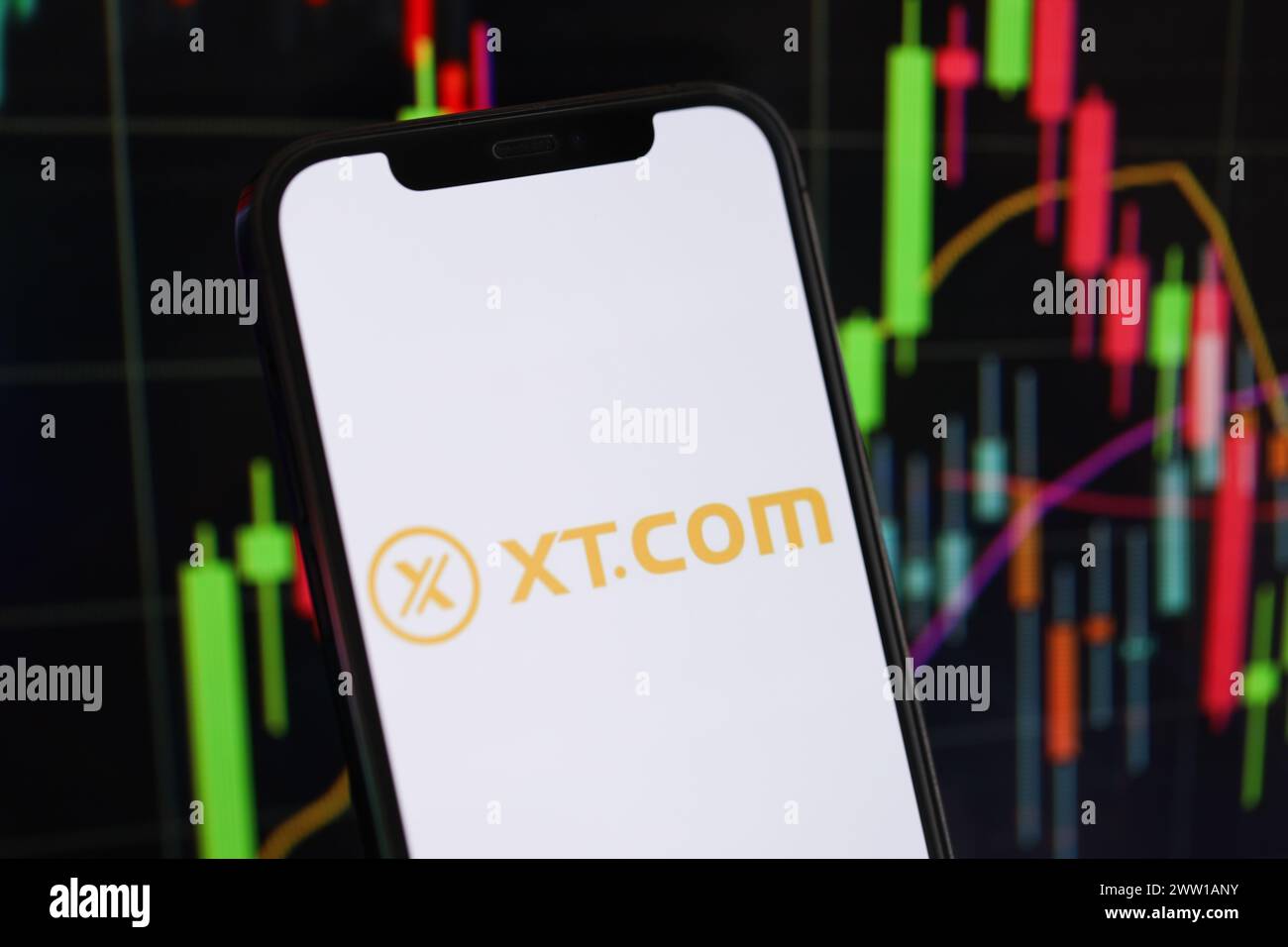 KIEW, UKRAINE - 15. MÄRZ 2024 XTcom-Logo auf dem iPhone-Display und Kryptowährungswertdiagrammen. Portal für den Austausch von Kryptowährungen Stockfoto