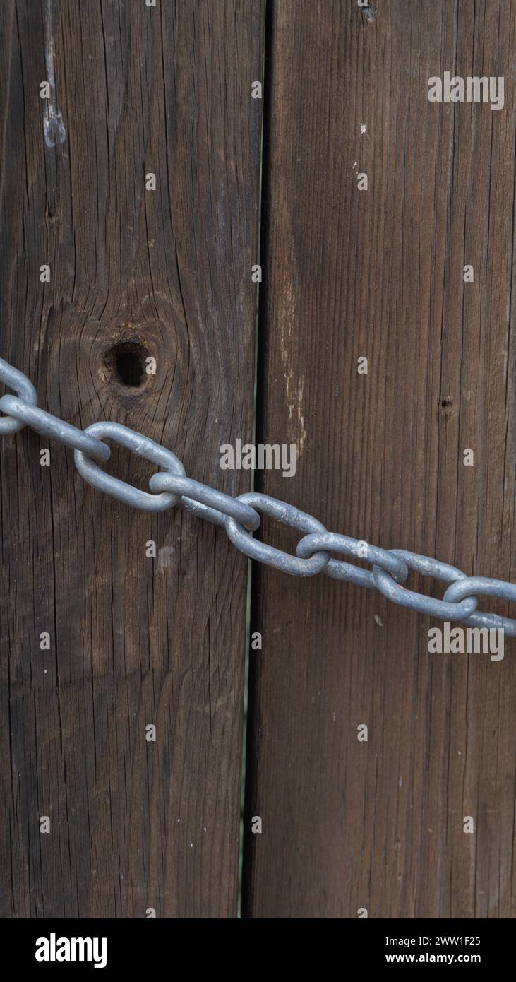 Stabile Metallkette, strukturierter Holzhintergrund, Vintage-Feeling, starker Kontrast Stockfoto