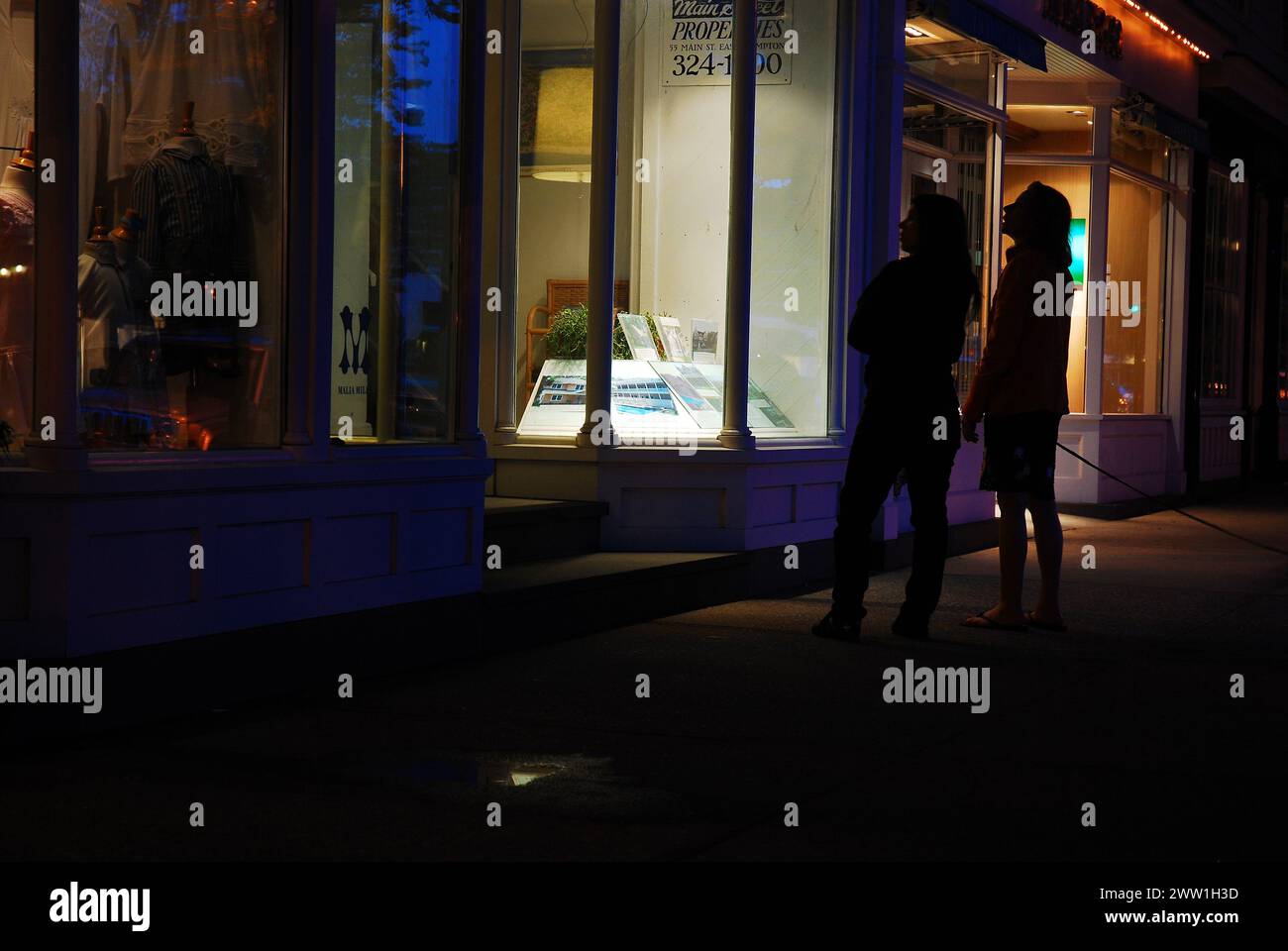 Zwei Frauen halten abends auf dem Bürgersteig in den schicken und luxuriösen Geschäften in East Hamptons, einem Teil der Hamptons Stockfoto