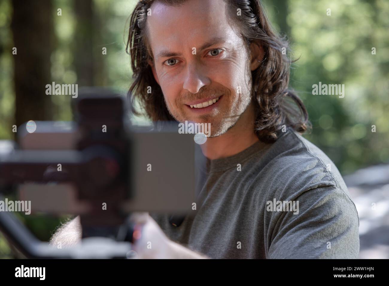 Content Creator verwendet. Ein Handy-Gimbal zum Filmen in der Natur mit einem verschwommenen Wald im Hintergrund Stockfoto
