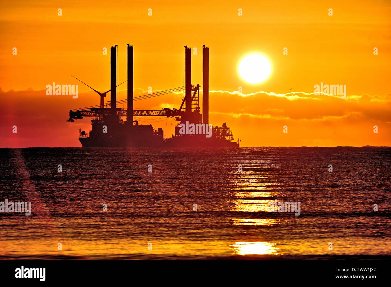 Vole Au Vent Offshore-Versorgungsschiff Jack Up Rig vor Blyth bei Sonnenaufgang mit goldenen Wolken und Sonne direkt über der Nordsee vor Anker Stockfoto
