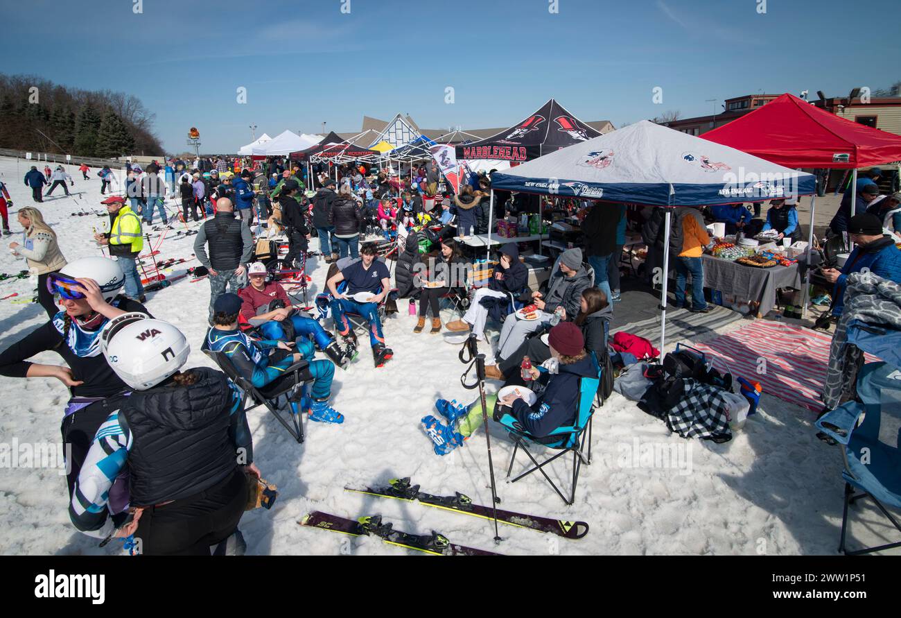 Massachusetts Interscholastic Athletic Association (MIAA) 2024 High School Alpinski jährliche Staatsmeisterschaft Slalom und Giant Slalom im Skigebiet Wachusett Mountain in Princeton, MA. Am frühen Morgen im Skigebiet stellen sich die Fahrer des HS-Teams vor den Zelten am Fuße einer der Rennstrecken am Berg auf. Stockfoto