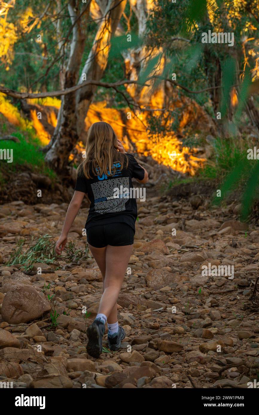 Frau wandert auf einem Steinweg entlang eines Flussverbandes im Wald. Stockfoto